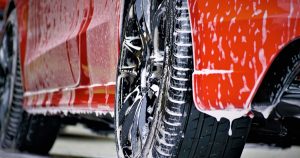 A red car with black wheels covered in soap suds