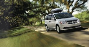 A silver 2019 Dodge Grand Caravan with a roof cargo carrier driving in a Wichita, KS park